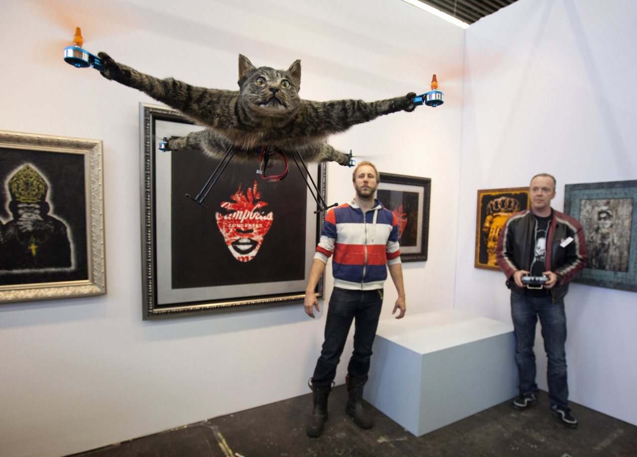 The Orvillecopter by Dutch artist Bart Jansen (back L) flies in a gallery as part of the KunstRAI art festival in Amsterdam June 3, 2012. Jansen said the Orvillecopter is part of a visual art project which pays tribute to his cat Orville, by making it fly after it was killed by a car. He built the Orvillecopter together with radio control helicopter flyer Arjen Beltman (back R). REUTERS/Cris Toala Olivares (NETHERLANDS - Tags: SOCIETY TPX IMAGES OF THE DAY)