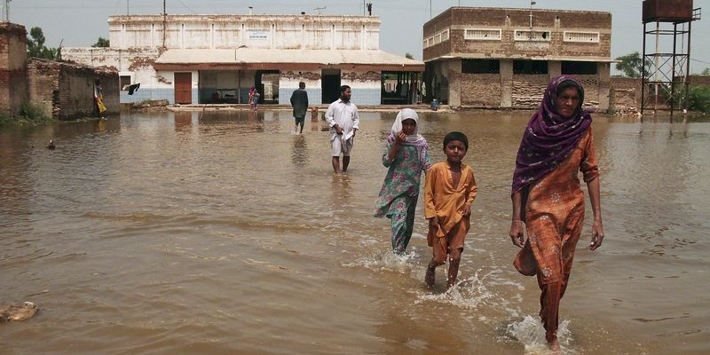 A family wades through flood waters in Dera Allah Yar, located in the Jaffarabad district of Balochistan province, August 6, 2013. Monsoon rains have claimed more than 80 lives in Pakistan, according to local media on Monday. Incidents of housing collapses, drownings and electrocution contributed to the increased death toll, Sindh Information Minister Sharjeel Inam Memon said. REUTERS/Amir Hussain (PAKISTAN - Tags: DISASTER ENVIRONMENT) - RTX12BQ0