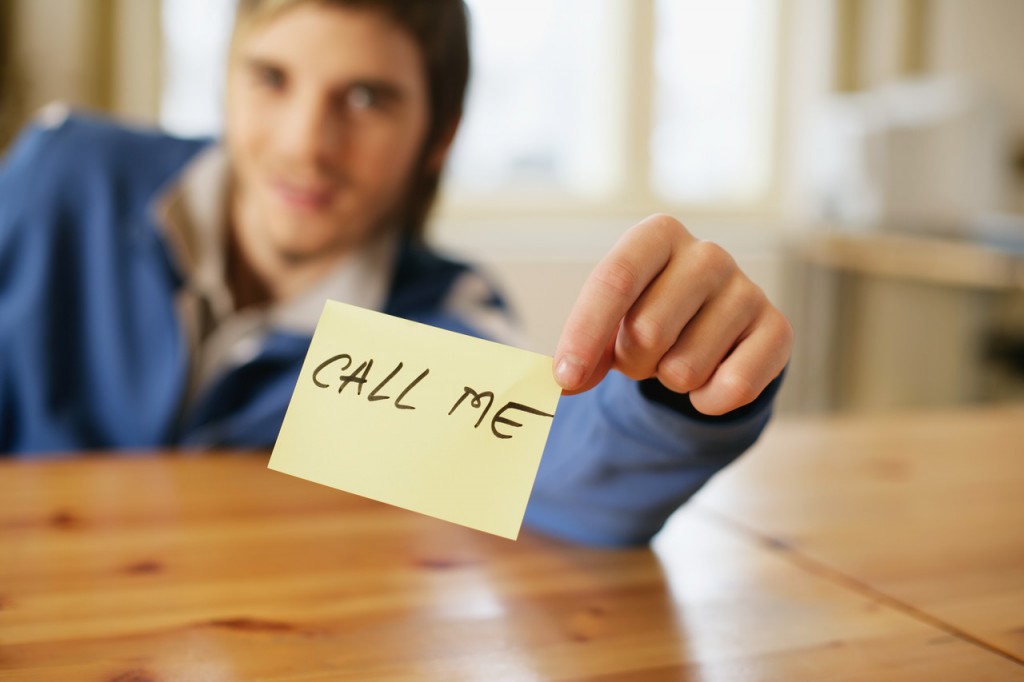 Man holding a note that reads 'call me' --- Image by &copy; Royalty-Free/Corbis